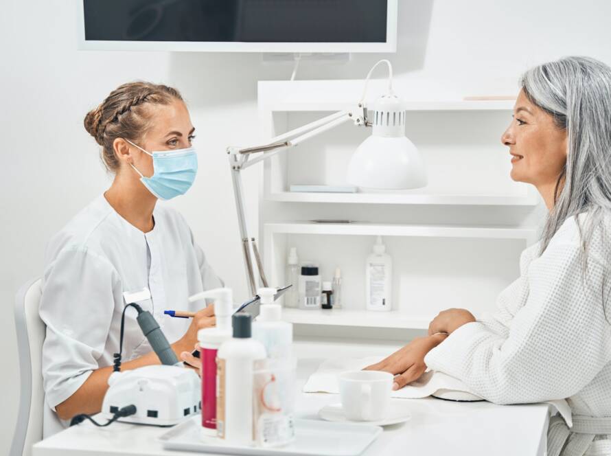 Cheerful aged client looking at her beauty master