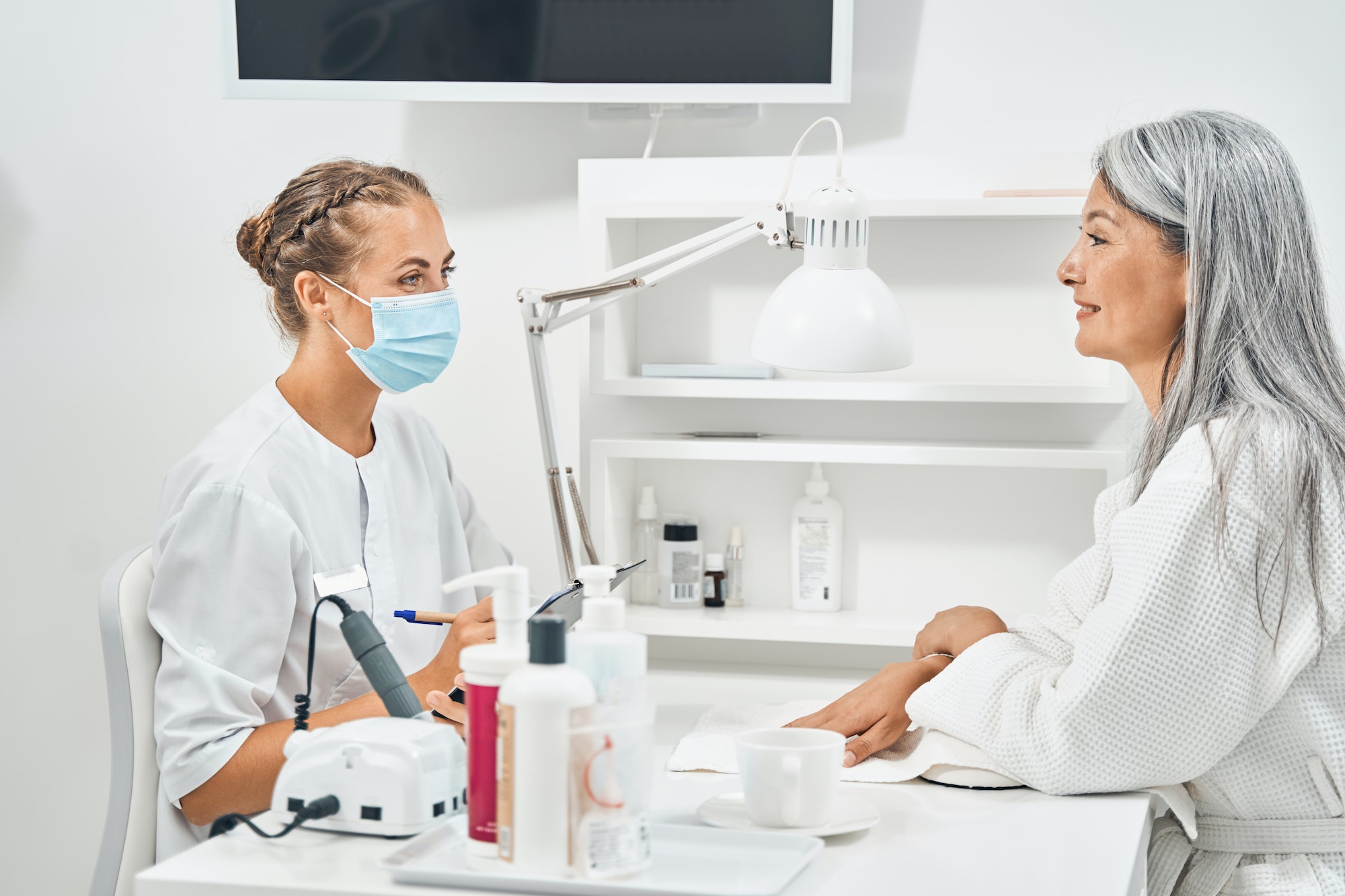 Cheerful aged client looking at her beauty master