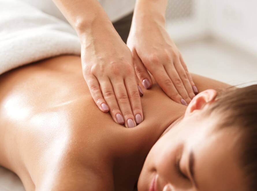 Young woman enjoying therapeutic neck massage in spa